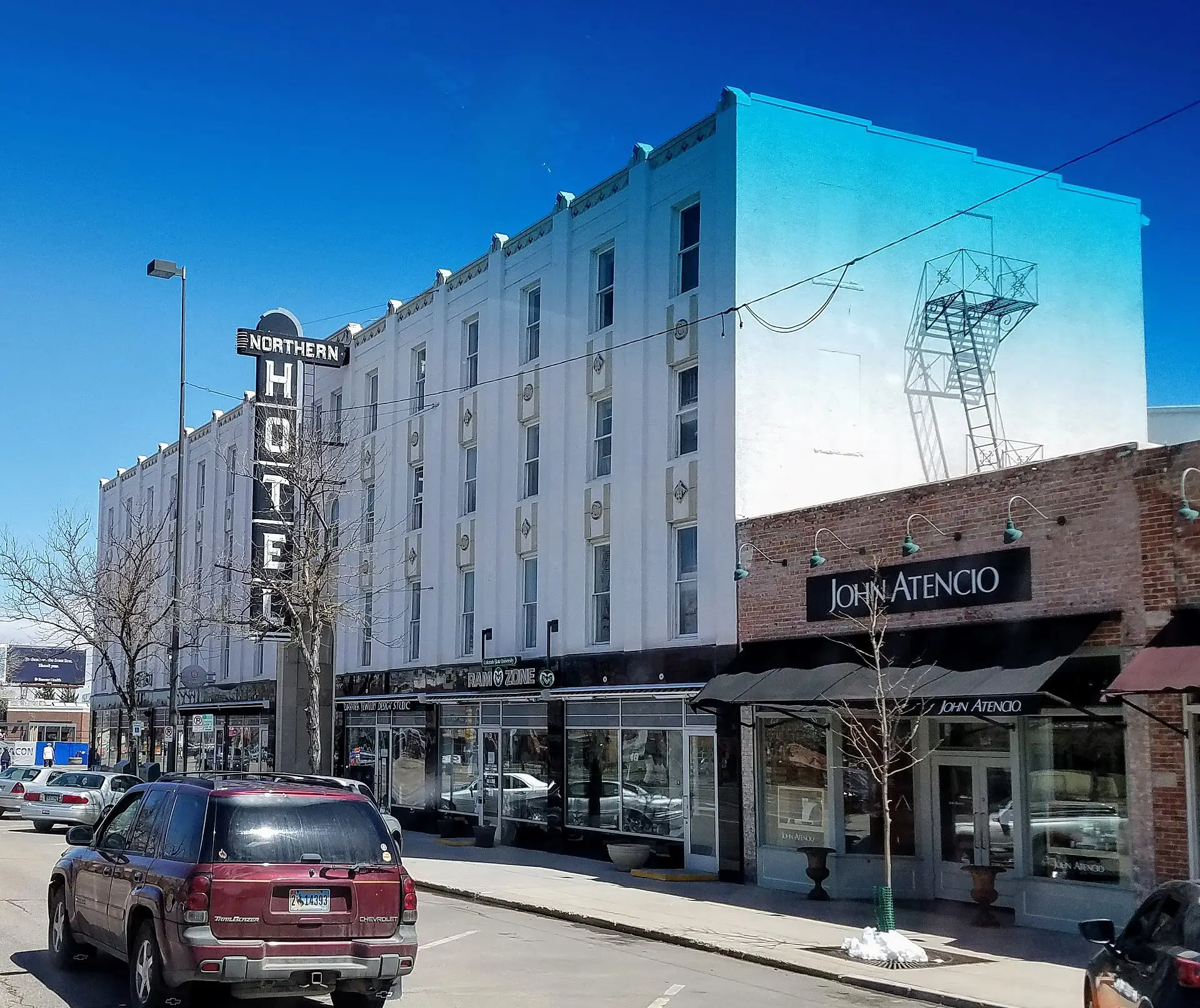 The Northern Hotel on College Avenue in Old Town Fort Collins, its vertical neon sign and white art-deco front beside a brick storefront under a deep blue sky