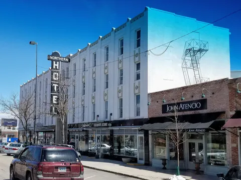 The Northern Hotel on College Avenue in Old Town Fort Collins, its vertical neon sign and white art-deco front beside a brick storefront under a deep blue sky
