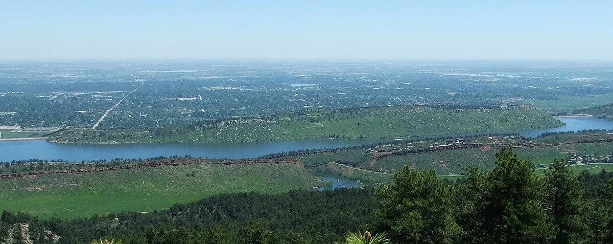 Horsetooth Reservoir from the ridge above it, the long lake between hogbacks with Fort Collins spread across the plains beyond