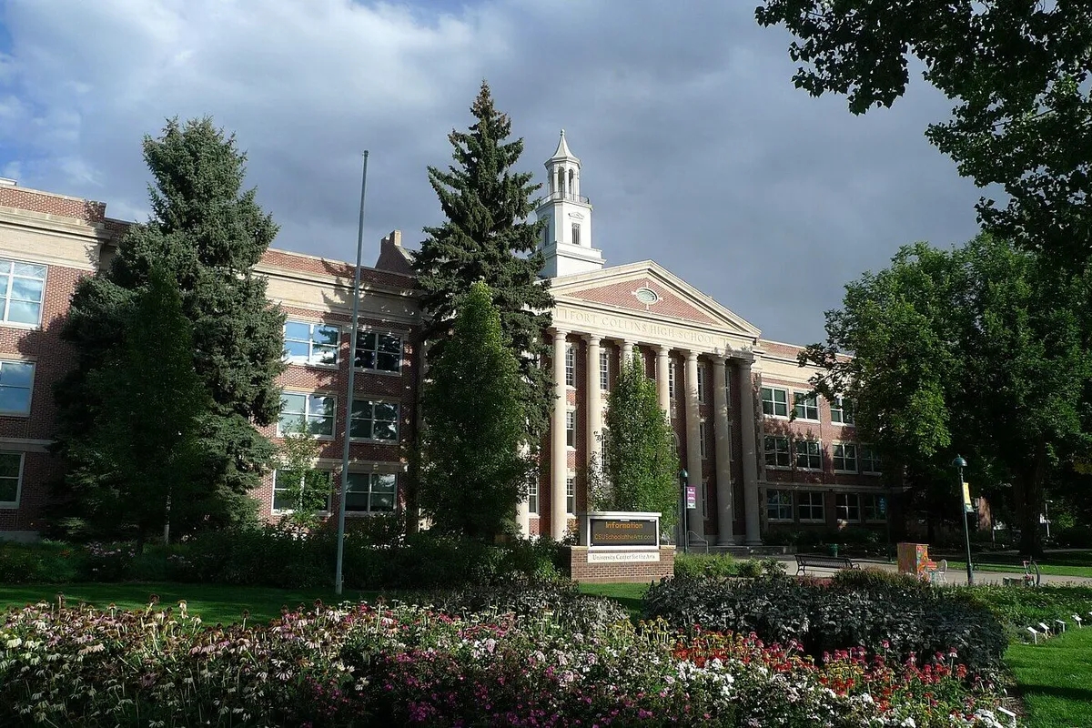 The columned, cupola-topped former Fort Collins High School on Remington Street, now CSU's University Center for the Arts, behind beds of summer flowers.